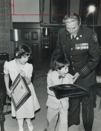 Hero's children, An excited Jamie Fikis, 6, and his 8-year-old sister, Kristin, carry Ontario Medal for Firefighter's Bravery and citation honoring th(...)