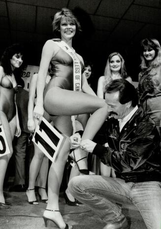 Star legs at The Star, Miss Legs Canada 1984, Karen Marin, 21, flashes her winning legs and a wide smile as she gets help with a shoe strap during the(...)