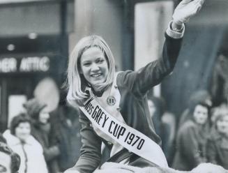 Miss Grey Cup, Nancy Durrell, who came to Toronto as Miss Montreal Alouette, acknowledges the cheers of the crowds as the parade winds its way from Va(...)