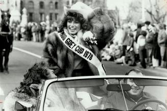 Miss Grey Cup, Lynn MacKenzie, 21, of Calgary, holds her hat as winds whip parade