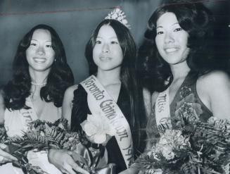 Three beautiful Asian women in sashes hold flowers and pose, smiling.