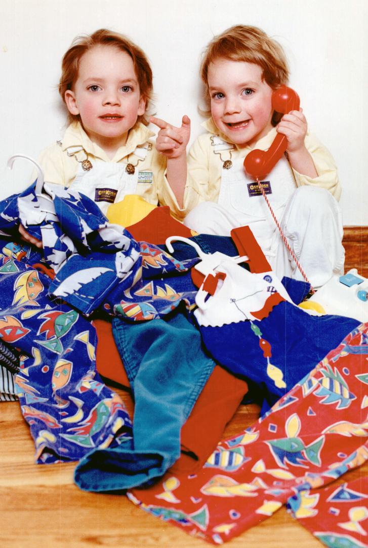 Dressing for two, Twins Dylan, left, and Malcolm McNeill, 3, preview goods for the Toronto Parents of Multiple Births Association's sale of used cloth(...)