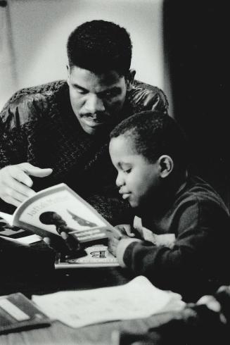 Ishmael Sinclair, 6, and volunteer Charles Clarke review a book in a tutoring program run by the Jamaican Canadian Association