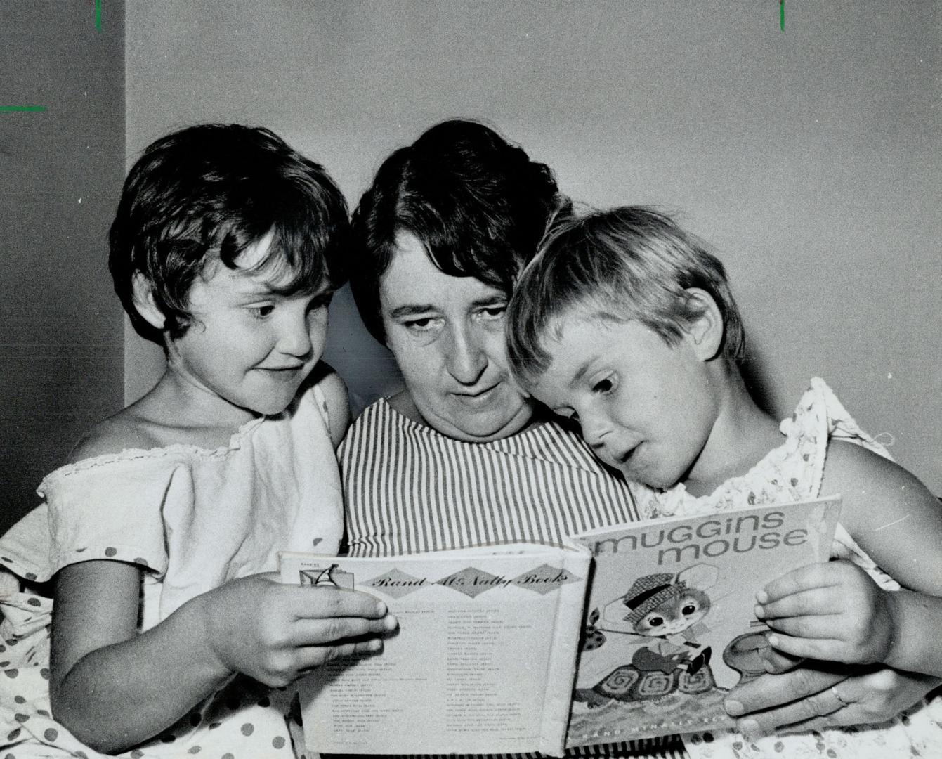 Perhaps for last time, Mrs. Arthur Timbrell reads bedtime story to the little sisters she wants to adoptéPeggy (left) and Valerie. Children's Aid Soci(...)