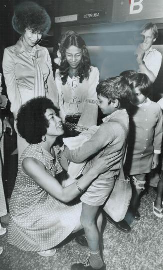 A group of women and children smiling and hugging.