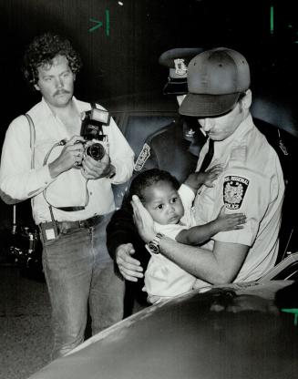 Taken to safety: A Peel Regional Police officer carries a baby believed to be Tanya Henriques, 10 months, whose parents were killed by a man who later committed suicide yesterday in Mississauga