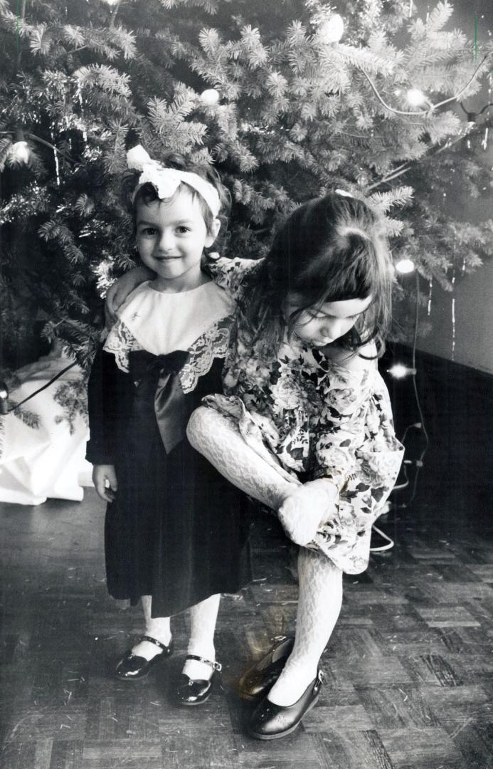 Jacquie Moir, 3, left, smiles as Timea Keller, 4, leans on her while checking her stockings yesterday