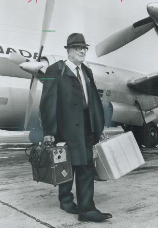 On a Mission of Mercy, Rev. Roy Essex carries portable respirator gear as he lands at Thunder Bay to bring aid to Waino Poutanen, victim of lung paralysis