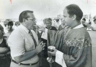 Italians' big day, Rev. Peter Gioppato gives communion to Etobicoke Mayor Dennis Flynn during an outdoor service marking the official start yesterday (...)