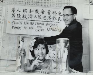 Rev. Yiu Shan Lee puts up a sign in the Chinese United Church announcing bazaar which helped raise $1,000 for Hong Kong refugees. Little Mariann Lee a(...)