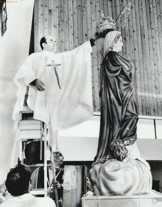 Statue of Mary crowned, Rev. Anthony Liotta, of Italy, places crown yesterday on statue of Mary Immaculate at St. Wilfred's Church, Finch Ave. near Ke(...)