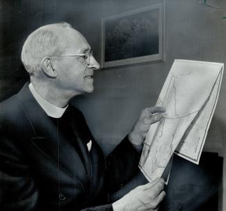Canon Marsh studies a map of his new charge, He has been elected Anglican Bishop of the Yukon