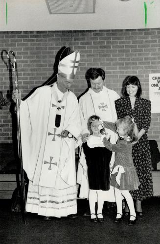Canadian first: Former Anglican cleric Rick McKnight is ordained as a Roman Catholic priest, with him are his wife, Evelyn, daughters Megan, 7, and Alanna, 5, and Emmett Cardinal Carter
