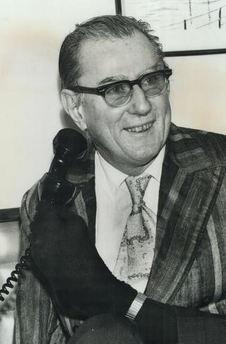 Closeup of Rev. Harold Wilke, of New York holding telephone to ear with his foot, note the watch band from his watch he has around his left ankle