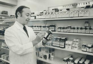 Pharmacist Ben Clodman takes down a bottle of pills in his drug store