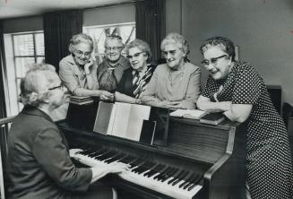 The Six Harpley Sisters gather around the piano at the Isabel and Arthur Meighen Lodge, 100 Davisville Ave