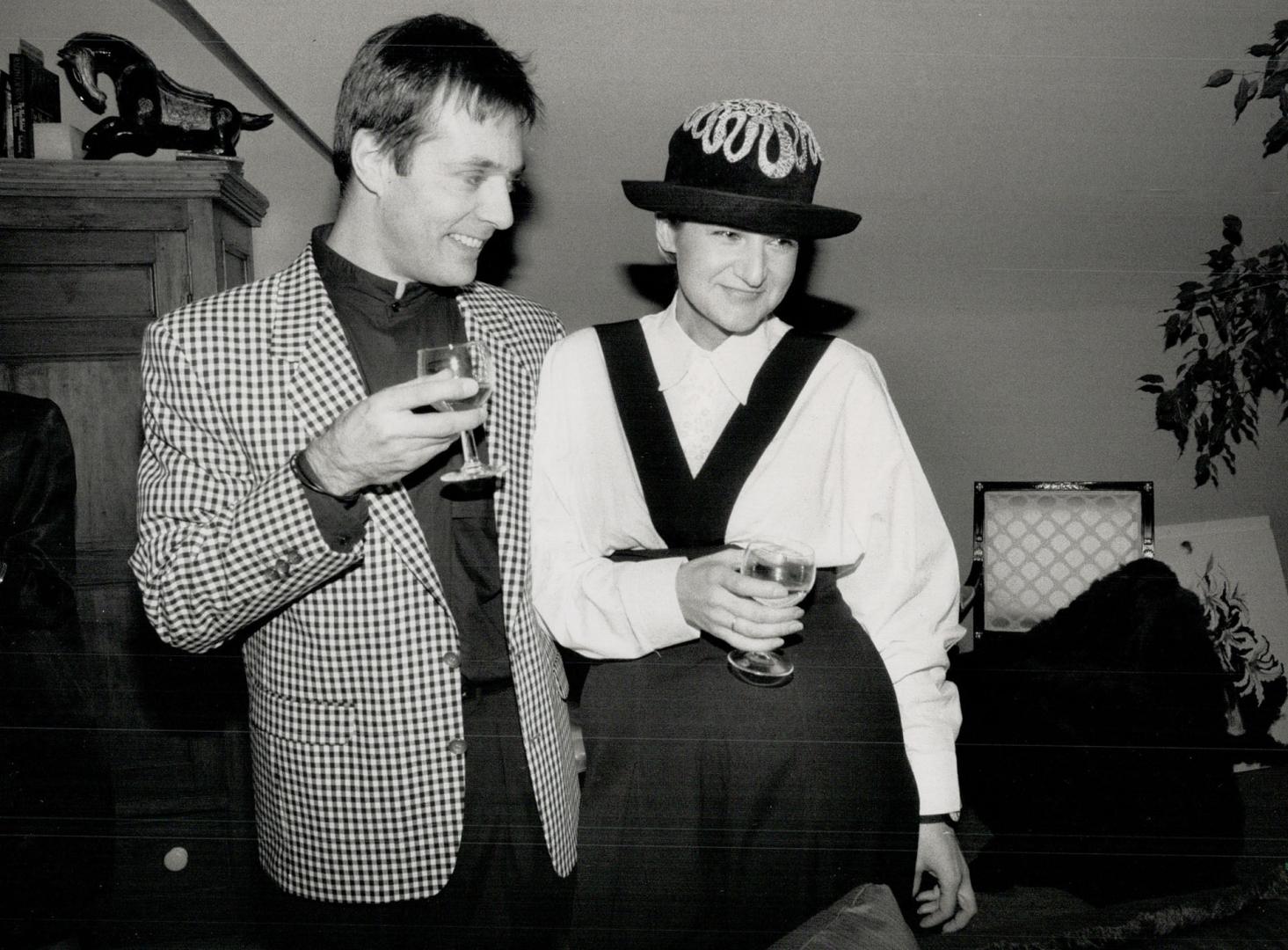 Above, designer Mariola Mayer in high cut pants with removeable cross strap, of her own design, shirt of many buttons, and bowler topped with filigree metal work, with fiance Christopher Mason