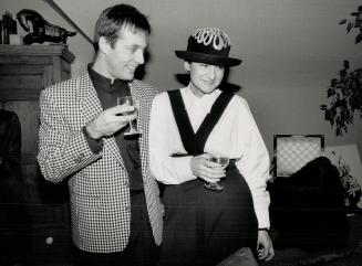 Above, designer Mariola Mayer in high cut pants with removeable cross strap, of her own design, shirt of many buttons, and bowler topped with filigree metal work, with fiance Christopher Mason
