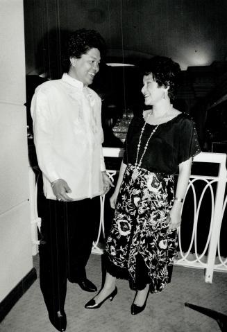 Hospital worker Verth Bugtong, wearing the traditional embroidered shirt called a barong, above, chats with Manila-based couturiere Patis Tesoro, who is wearing one of her own designs