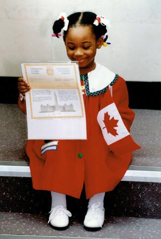 Nichole Lindo, 3, beams as she gives her citizenship documents the once -over