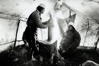 Sylvester Riche (left) and band chief Daniel Ashini set up a stove in their tent after heading out to a fishing camp (below)