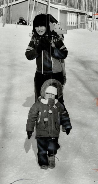 Unidentified mom, with youngster in front and baby on back, all bundled against the cold (far left)