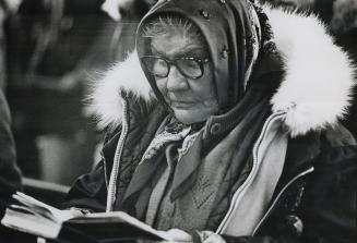 A cree woman follows the service in her prayerbook in the Anglican Church at Fort George, Queec
