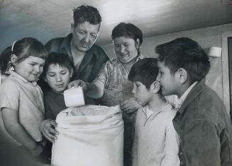 A sack of home-milled flour brings happy smiles to the faces of Albert Malbeauf and his family in Meadow Lake, Sask