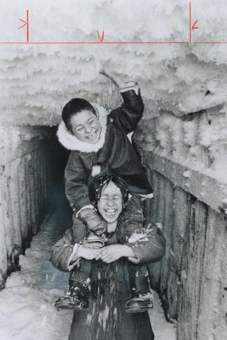 Eskimo children Rita, 8, and Jimmy Carpenter, 6, play on ice at the entrance to a pingo, an underground cavern used to store pelts. It used to be the (...)