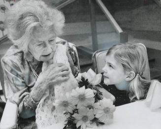 Celebrating a 100th Birthday, Celebrating her 100th birthday, Amelia (Minnie) Brett admires flowers with Jennifer McCullough, 5, one of her 23 great-g(...)