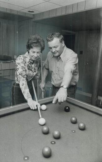 Riding a winning streak, Bessie Jacobs gets some advice from her husband, Bob, as she lines up a billiard shot in the home they completely refurnished(...)