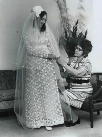 Proud grandmother Mrs. Mary Spiegel arranges the veil on the wedding gown she made for her granddaughter, Mrs. Milton Avruskin, who was married last n(...)