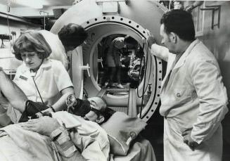Nurse Jennifer Waring and chief operator Keith Howard (right) prepare Harold Norton for treatment in decompression chamber