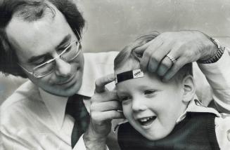 An instant thermometer is applied to forehead of 3-year-old Andrew Van by Dr. Maxwell Axler. He'll know within 60 seconds Andrew's temperature. He's u(...)