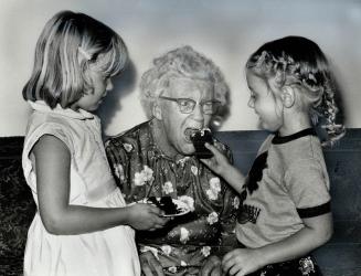 Alice Rowland takes a bite of her 90th birthday cake, offered by Kathleen and Marine Rowland, her 5-year-old great-grandchildren. Mrs. Rowland also received a plaque signed by Premier Davis