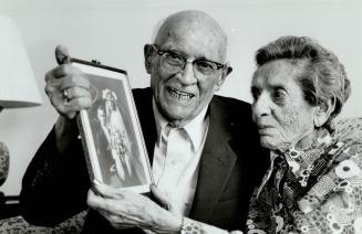 Togetherness: Samuel and Sarah Bernstein with a picture of their wedding, which took place in Toronto 70 years ago today