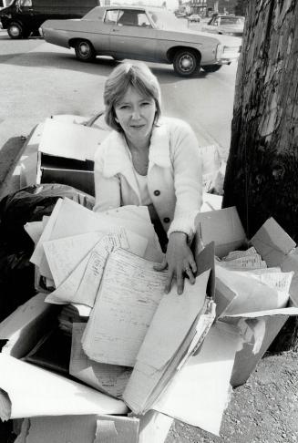 Open books: Debbie McPhee of North York kneels beside some old medical records found blowing around an apartment building parking lot yesterday by Lettty Young