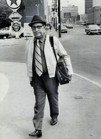 A victim of the lung disease emphysema, Hilliard Thompson Biggar walks along the street with his portable oxygen system