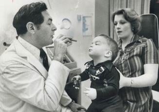 Dr. Henry Brent, a doctor at the Hospital for Sick Children's contact lense clinic uses a light in order to examine the eyes of 18-month-old Wayne Mil(...)