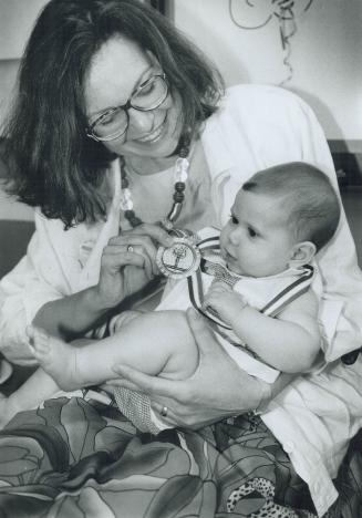 Nurse Linda Smith plays with 6 1/2-month-old Shannon Lowery's gold medal at the 1992 Celebration of Life