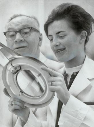Giant magnifying glass used for examination of cultures is swung into place by laboratory technicians Arthur Telford and Elizabeth Borman, two of team(...)