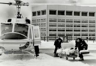Helicopter carrying patient from Barrie lands on roof of Hospital for Sick Children and paramedics Ken Murray (left) and Dick Hyatt begin last leg of mercy mission