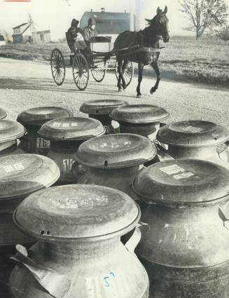 Amish Buggy on a road in Aylmer passes a stack of the milk cans that the Ontario Milk Marketing Board wants to abolish