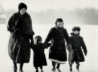 A Mennonite mother and her children walk along icy path