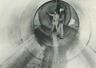 Search for boy goes underground, Andy Try, 14, and Peter Ostrowskie, 12, beam a flashlight down a side tunnel inside the network of storm sewers in R(...)