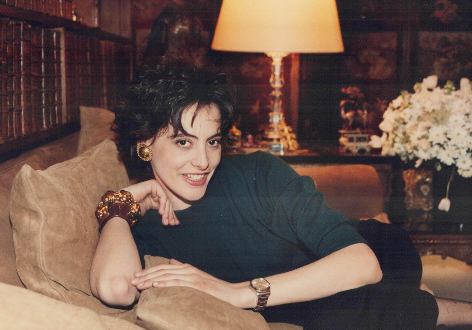 Ines de la Fressange curls up on a couch in Coco Chanel's Paris apartment wearing a cashmere sweater -- buttoned at the back