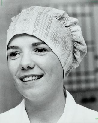 Susanna Hagan does her job in the operating room with her hair hidden under cover-up in orange and pink print