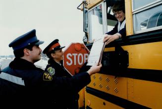 Safety first: OPP Constable Dave Thomas and Constable Caria Ferguson of Halton Region Police show Laidlaw Transit school bus driver Betty Beecroft a Bus Watch information sheet