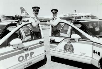 Trading places: The RCMP's Constable Keith Baltrus, left with his temporary OPP cruiser, and OPP Constable Kelly Wilson with his borrowed Mountie car, have switched jobs