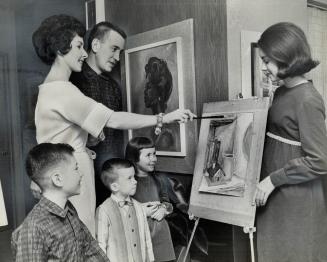 The Mills Family, wearing some of mother's handiwork, admires painting she's preparing for February show